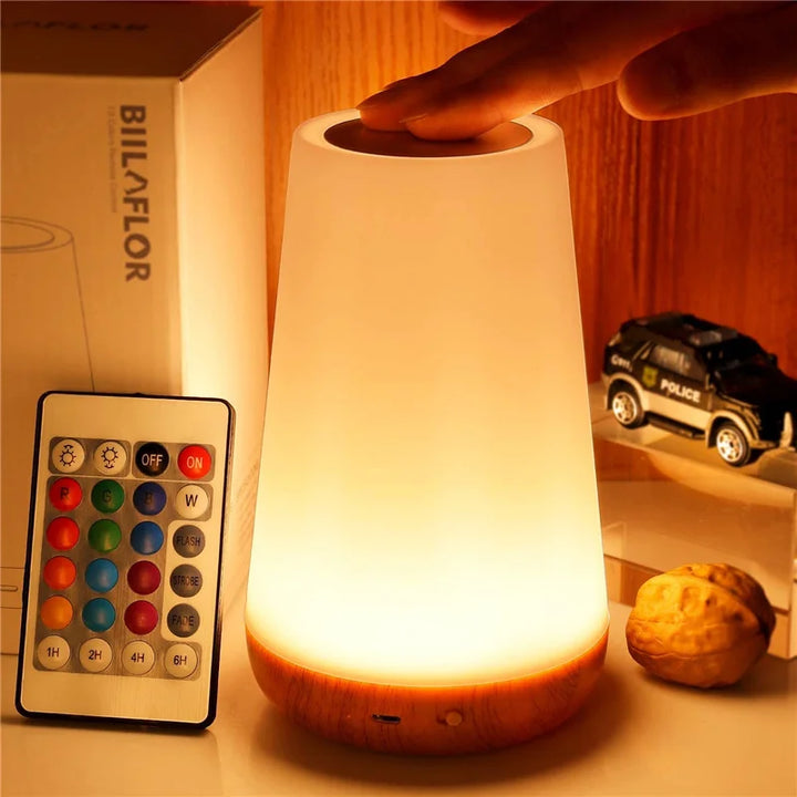 Cylindrical accent lamp glowing warm yellow with a remote control beside it